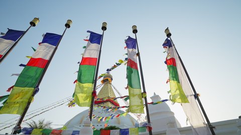 Colorful prayer flags on flagpoles flutter at white festive Swayambhunath stupa