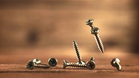 Self-tapping screws fall on the table. On a wooden background. Filmed is slow motion 1000 fps. High quality FullHD footage - Powered by Shutterstock - Get 15% off with code: PIKWIZARD15