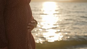 Close-up view 4k stock video footage of big female belly isolated on sunny sunset golden sea water background