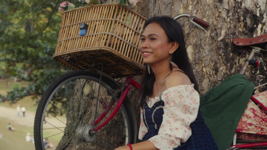 Transgender Asian woman standing with her bike and looking at the camera.