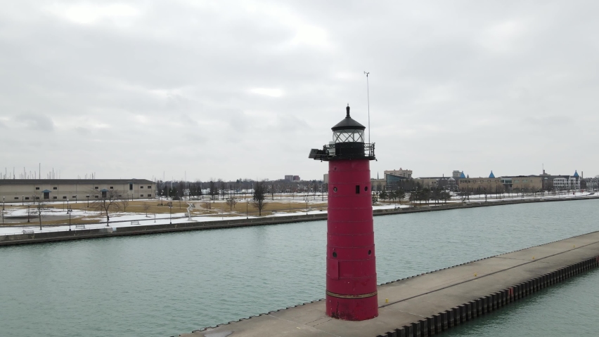 Aerial view of lighthouse in Kenosha, Wisconsin, on Lake Michigan. Light snow fall in the park. Calm waters in the canal. Sculptures in the park across canal. 