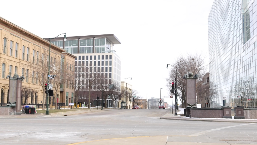 Street intersection in Madison, Wisconsin. Traffic signals on each corner. Bare tree branches. Light snow seen on the ground. 