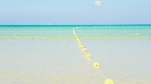 Buoyant swim lane section divider safety line. Yellow marker swim area buoys on sea. Yellow floating buoy over ocean.