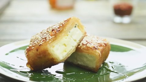 The chef sprinkles thyme over feta cheese in crispy filo pastry, served on a plate.