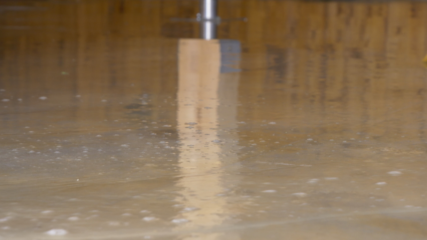LOW ANGLE, CLOSE UP: Person uses a straw broom to sweep the flooded floor after an episode of heavy rain. Broom with rough straw bristles sweeps away the dirty water covering the basement floor. | Shutterstock HD Video #1084440193