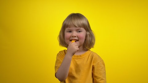A cute little girl with short hair is blowing in a whistle with closed eyes