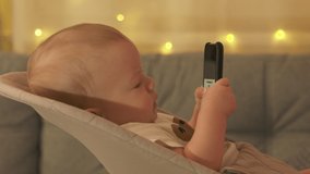 Cute little child using mobile device, baby boy watching movie on TV and using smart phone at same time. High quality 4k footage