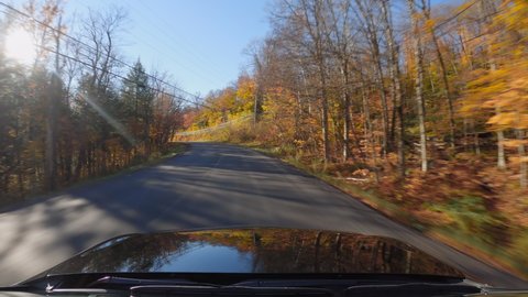 Driving a car on Vermont asphalt road full of colorful trees in Autumn season. POV