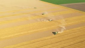 Drone shot flying over combine harvesters working on farmland during harvesting. Gathering crops from a bird's eye view. Agronomy region Ukraine, Europe. Cinematic footage. Filmed in UHD 4k video. 