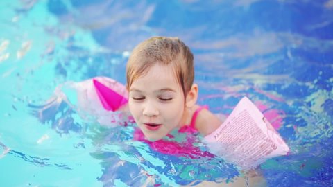 time-lapse. a funny little girl swims and plays in inflatable armbands in a pool. safety of children on the water. inflatable toys for swimming and playing in the water. swimming training.