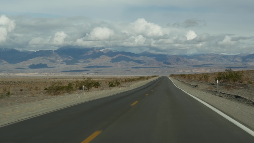 Road trip to Death Valley, driving auto in California, USA. Hitchhiking traveling in America. Highway, mountains and dry desert, arid climate wilderness. Passenger POV from car. Journey to Nevada.
