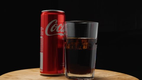 Highball glass with Coca-Cola and ice, with a red aluminum can of Coca-Cola on a black background. The camera flies around. Parallax effect. Russia, Krasnodar, December 24, 2021