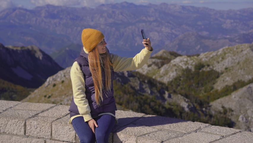 A young woman traveler visits the view point on the top of the Lovcen mountain. The Mausoleum of Petar II Petrovic-Njegos