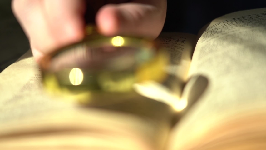 Close-up Hand with a magnifying glass and an old book. Knowledge accumulation and history concept