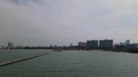 Aerial footage towards the right from a distance revealing the Pattaya Fishing Dock and the city in the horizon, Chonburi, Thailand