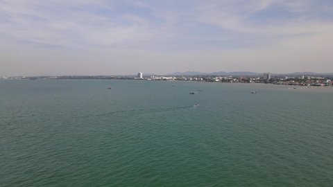 Ascending aerial footage showing the beachfronts of Pattaya city, a speeding boat and fishing boats, Pattaya and Beachfronts, Chonburi, Thailand