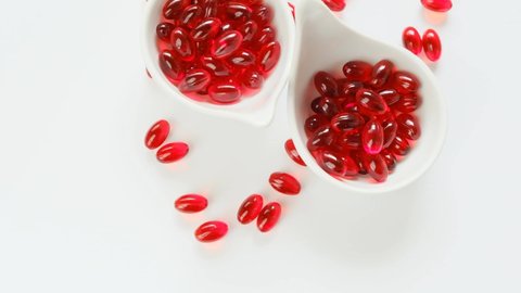 Krill oil red capsules in white ceramic cups on a white background.omega fatty acids.Natural supplements and vitamin