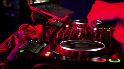 Close-Up of Dj Mixer Controller Desk in Night Club Disco Party. DJ Hands touching Buttons and Sliders Playing Electronic Music . High quality 4k footage