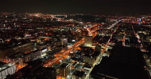 Aerial establishing shot of city at night. Dark sky as traffic flows on highway. Birds eye view.