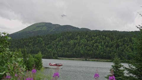 Floatplane On Water Surface With Lush Forested Mountain In Alaska On A Cloudy Day. timelapse