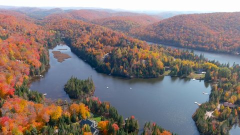 4K camera drone captures stunning autumn foliage colors and secluded houses on the lake.