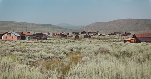 Wide dolly shot of an old gold rush, mining, ghost town in the desert of California