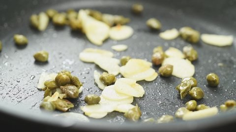 Frying garlic and capers in a frying pan.