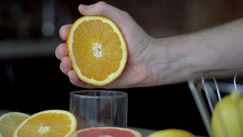A man squeezes orange juice with citrus juicer. Close-up of hands, oranges, juicer, healthy lifestyle