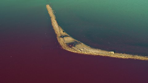 Aerial view romantic island at pink sea surface. Drone view colourful sea water surface. Saline beach line at pink blue water. Amazing seascape at summer. Salt mineral coastline. Meditative seashore