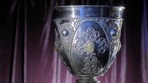 Close-up of an old decorated silver bowl and blue glare of light