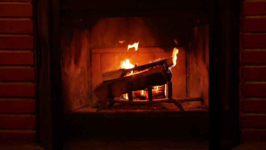 Fire in brick fireplace, firewood burning, wood blazing in cozy lodge, hut or cabin. Romantic weekend on winter holidays, fireside in warm cosy cottage house. Seamless looped cinemagraph background. Royalty-Free Stock Footage #1084519297