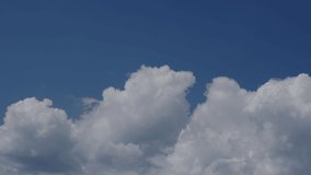 Close-up 4K time lapse video of white big clouds on a blue sunny sky. Summer blue cloudy sky time lapse. Effect of flying an airplane through the clouds.