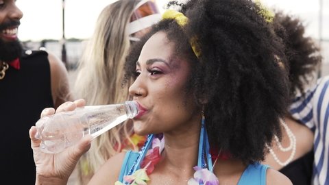 Carnival Party in Brazil, brazilian woman drinking water at outdoor festival dressed