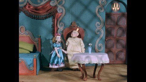 1940s: Hand holds shooting slate. Puppets. Bedroom. Little girl shakes head. Girl cries and buries head on king. Man embraces girl.