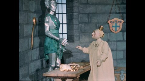 1940s: Puppets. Silver statue and king in castle vault. King bends to touch gold. Little girl cries on bed. Girl walks away. Hand holds shooting slate. Person kneels on set.
