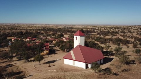 4K aerial drone video of Africa savanna hills and plains, tiny settlement Baumgartsbrunn and small white stone church west of Windhoek in central highland Khomas Hochland of Namibia, southern Africa