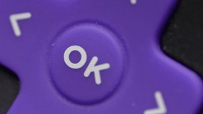 Closeup shot of a finger pressing the OK button on a remote control of a TV.