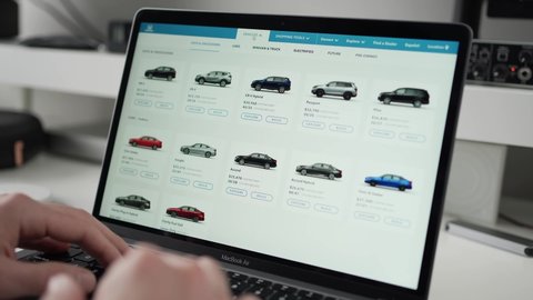 Shopping online on a laptop computer for a new car, looking at models and selecting a SUV. MONTREAL CANADA DECEMBER 2021