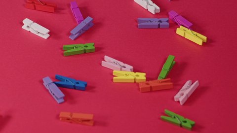 Wooden pegs in rainbow colors. Falling on red background.