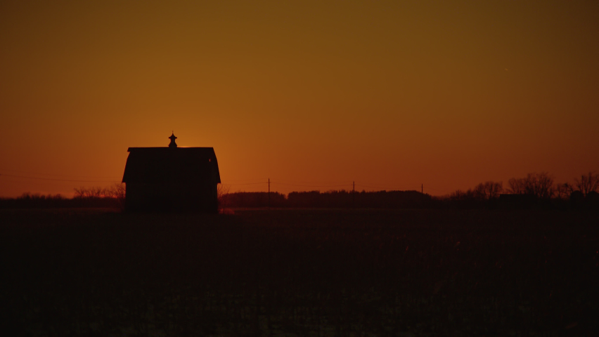 The sun rises behind a majestic old barn on a winter morning in Iowa.