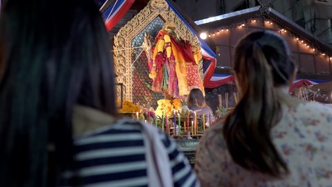 Young women praying to Ganesh God to bring luck and success, worship. Phra Pikanet Shrine, Huai Khwang, Bangkok, Thailand. 4k, 10bit, 422, 50fps, over the shoulder shot