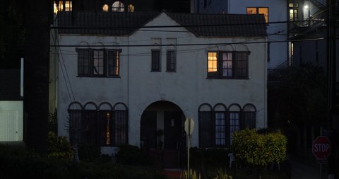 A nighttime establishing shot of a California townhouse with lights on in the bedroom window. Exterior with daytime match - 1072270616