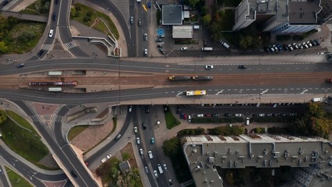 Aerial birds eye overhead top down panning view of transport in city. Pair of trams passing by each other on elevated road with tram tracks. Warsaw, Poland
