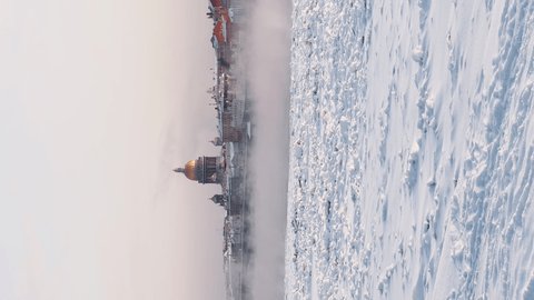 Slow motion footage of winter view of St. Petersburg at sunset, steam over frozen Neva river, huge ship, Isaac cathedral, car traffic on Blagoveshenskiy bridge