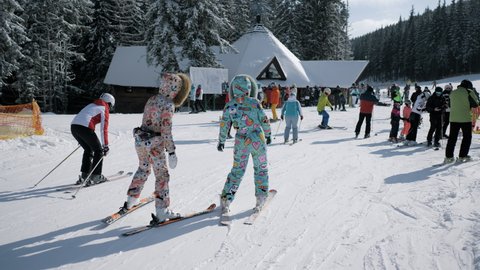 Bukovel, Ukraine, december 2021: Skiers going downhill dressed in funny ski suits in a resort, active rest in winter mountains