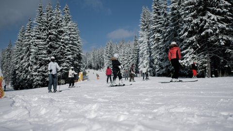 Skiers going downhill in a ski resort, active rest in winter mountains