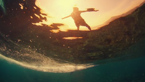 Surfer rides the ocean wave in tropical Maldives, split view of the surfer and underwater view of the rolling and breaking wave