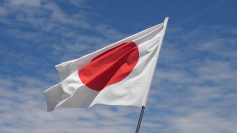 Japan Flag Waving in the Wind in Slow Motion Close Up with blue sky background. High quality 4k footage