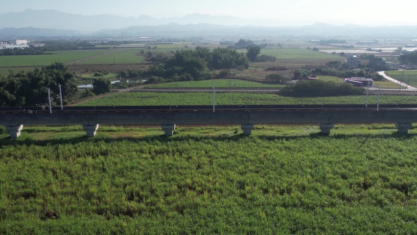 Aerial view of an bullet train over a sugarcane field in Taiwan Royalty-Free Stock Footage #1084576828