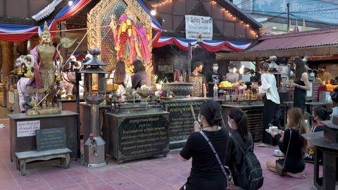 Asian young women praying to Ganesh God for love and success. People worship, holding joss sticks and offer food at Ganesh Shrine temple. 10bit, 422, 50fps. Huai Khwang, Bangkok, Thailand 15 Nov 2021